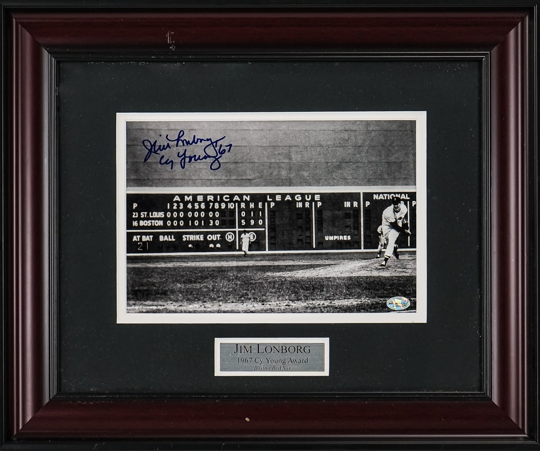 Jim Lonborg Autographed Photo: Photo of Jim Lonborg 1967 Cy Young Award Boston Red Sox with image of Green Monster score board in background, signed Jim Lonborg Cy Young 67. 6" x 9" image. 18" x 15" framed. Certified.