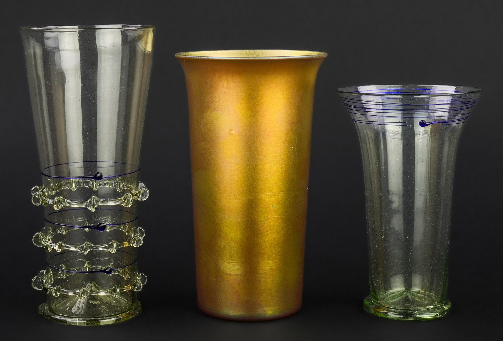 Steuben Gold Aurene and Venetian Tumblers: Early 20th c. Steuben gold iridescent Aurene tall flared tumbler, signed with stamp "Aurene" in ground pontil, accompanied by two delicate Venetian style tumblers with applied threaded decoration ht. 