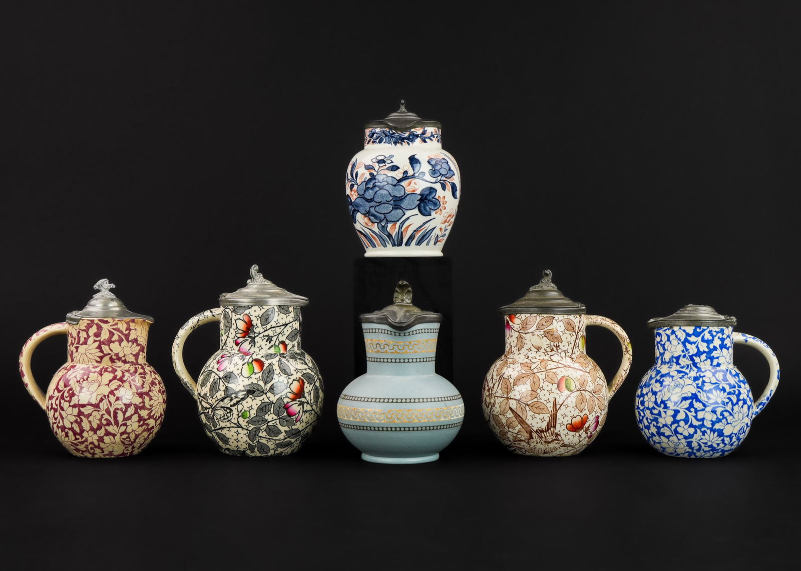 6 English Transferware Syrup Pitchers: A group of 6 English transferware syrup pitchers including Ningpo Wedgwood, and a Basalt with pewter lid signed Booth Hanley. Approx. 5 1/2" h. One top finial missing.