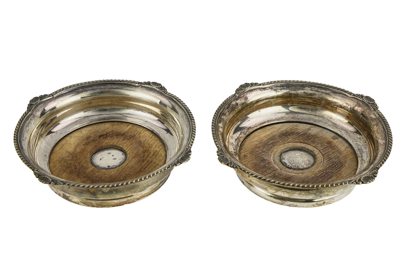Pr. Asprey London Sterling Silver Bottle Coasters: Pair of 1913-14 Asprey and Co. Birmingham sterling silver Edwardian era bottle coasters having oak inset bases with gadroon and shell rims, retailed by Asprey of London, some slight variations in turn