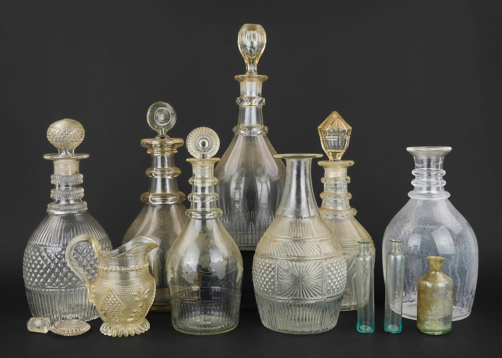 Early American Blown Glass Decanters: Early American blown glass (12 pcs)- decanters including blown 3 mold, French 3 mold miniature pitcher, attributed Lake Dunmore Glass medicine vials, stoppers, etc (some damage)