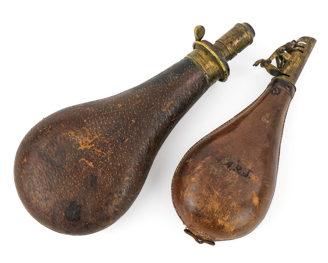 19th c Brass & Leather Shot Flasks: Two 19th c brass & leather shot flasks- both with adjustable brass dispensers, the larger one stamped James Dixon & Sons, Sheffield, Quick Loading Fireproof, the smaller stamped Am. Flask & Cap Co., l