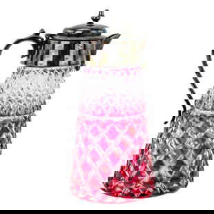 Cranberry Cut-to-Clear Syrup Pitcher with Sterling Silver Plated Lid: Cranberry glass syrup pitcher featuring a cut-to-clear diamond pattern. Topped with a sterling silver plated lid. Measures approximately 5.5" tall by 2.5" wide.