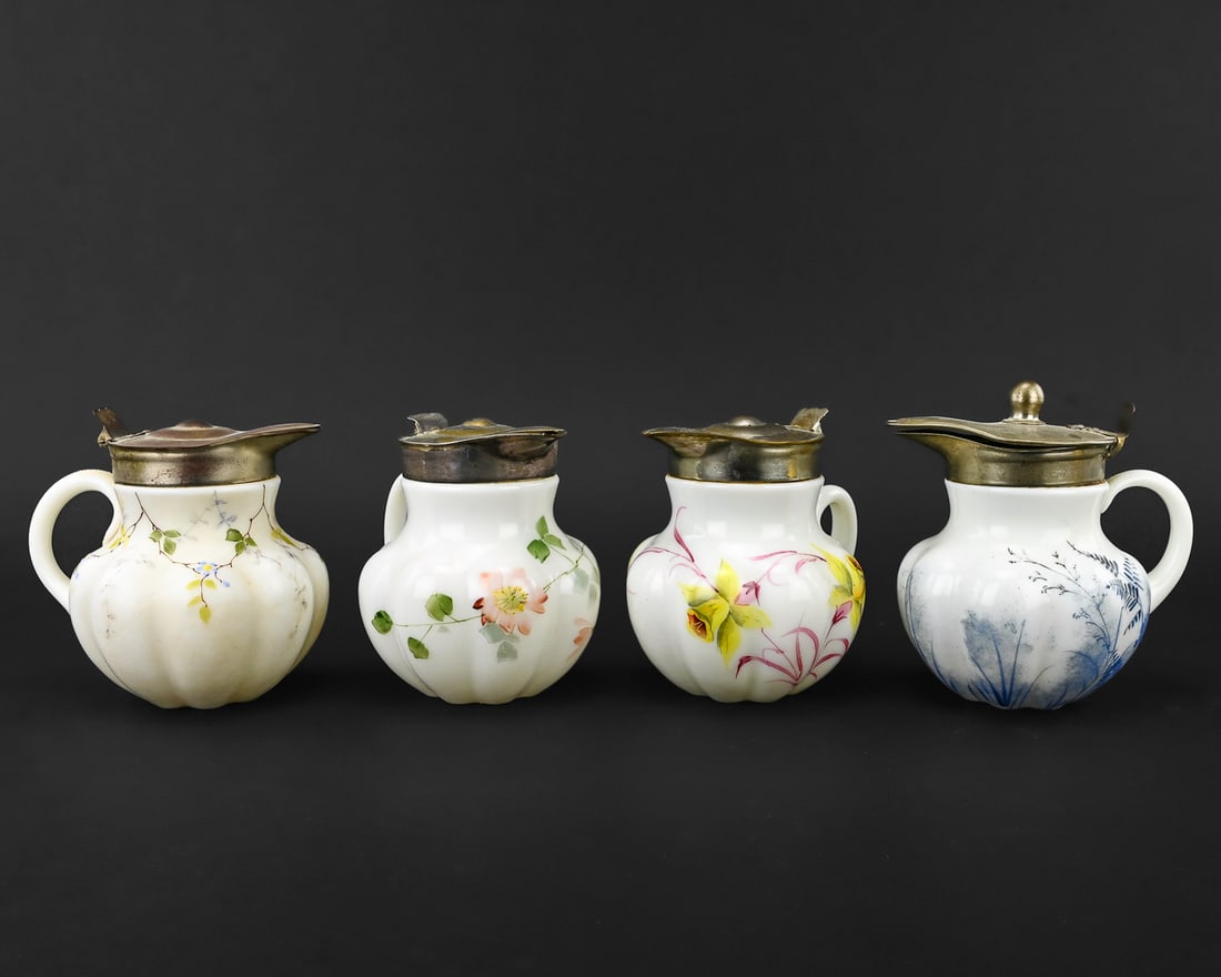 4 Milk Glass Syrup Pitchers with Painted Flowers: Group of four milk glass syrup pitchers, each hand-painted with floral motifs. All are attributed to Belknap, pattern P.86, and feature pewter lids. Each measures approximately 5" tall x 4" wide