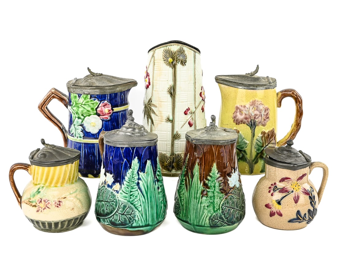 7 Majolica Syrup Pitchers with Pewter Lids: Group of seven majolica syrup or molasses pitchers, each with floral, leaf, or fern motifs in classic raised relief. All fitted with pewter lids. One is marked Holdcroft, a known 19th-century English