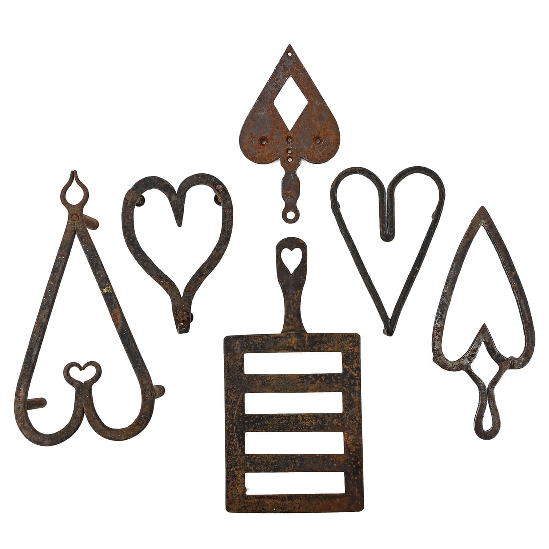 Early Wrought and Cast Iron Trivets (6 Pieces): Group of six early wrought and cast iron trivets, primarily heart-shaped. Includes one square trivet with attached handle measuring approx. 10" L (including handle) x 5" W. All retain original iron pa