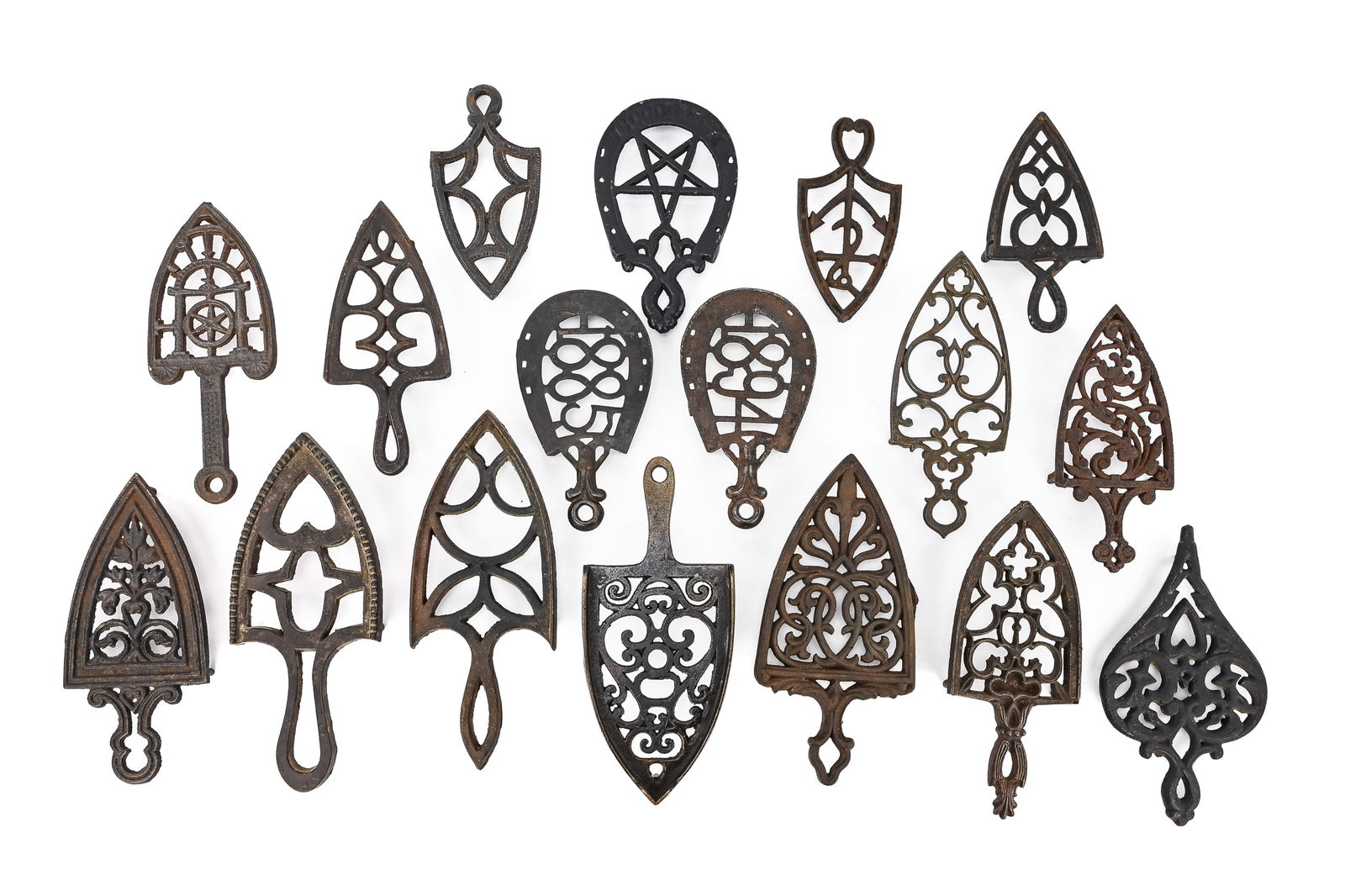 Group of 17 Nautical- and Horse-Themed Cast Iron Trivets: Seventeen cast iron trivets, mostly spade- and horseshoe-shaped, featuring nautical motifs such as anchors, stars, and sayings like “Good Luck.” All retain museum reference numbers. Sizes rang