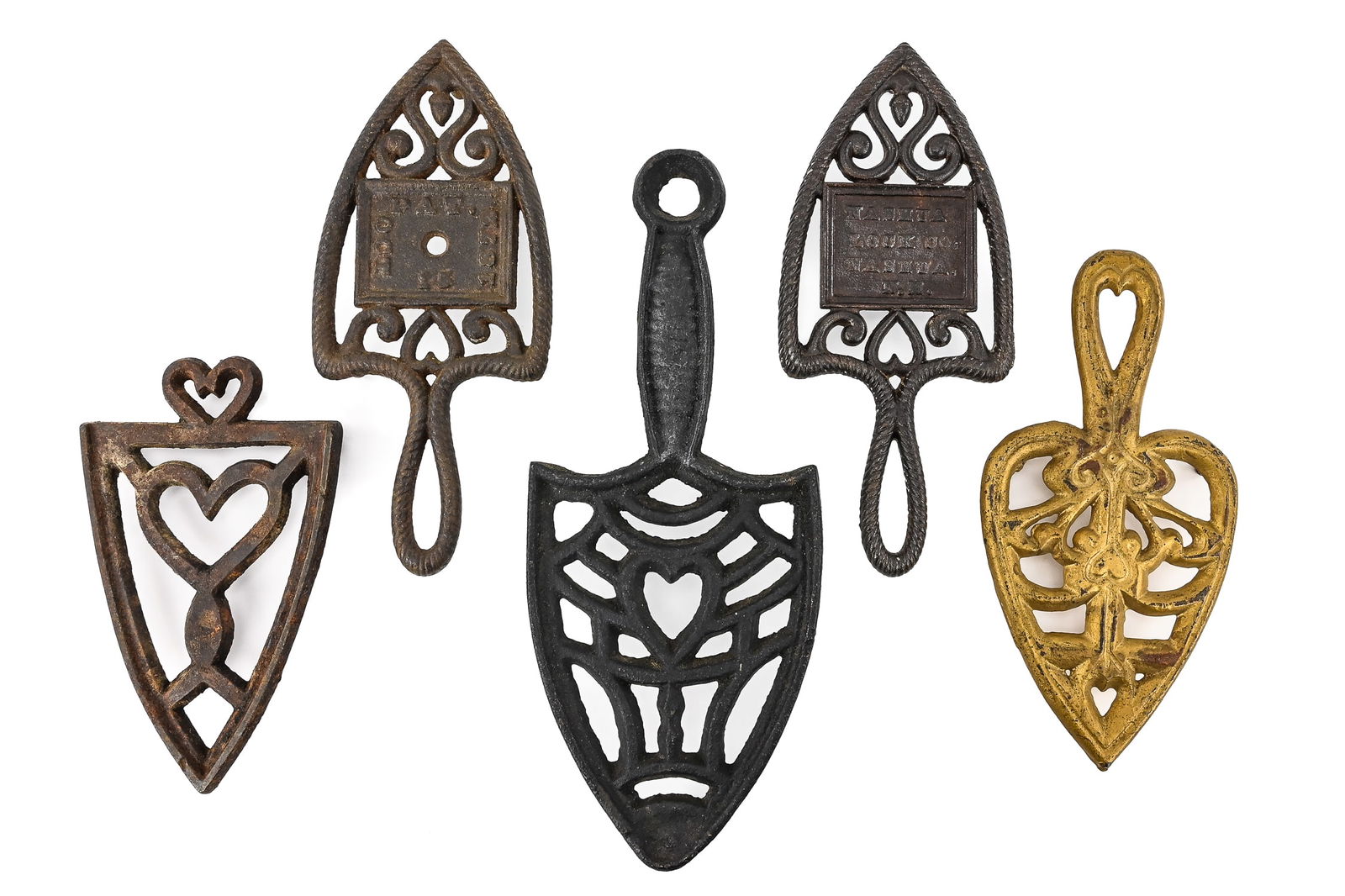 Two Cast Iron Trivets: Group of two cast iron trivets. One is a “Sad Iron” trivet by Wilton, measuring approximately 9" x 5". The second is by Virginia Metal Crafters, featuring oval shapes with horse or Red Riding