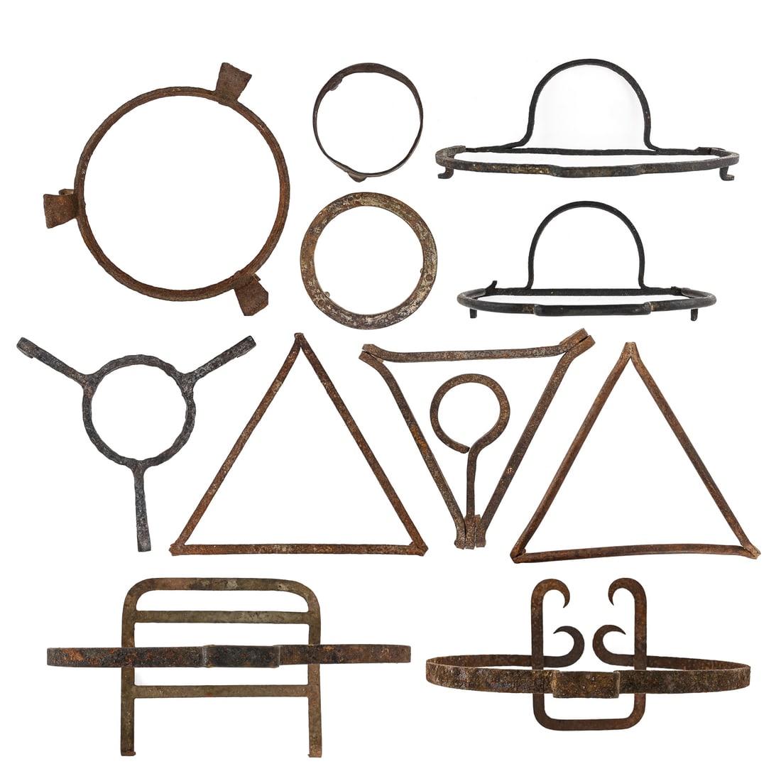 Cast and Wrought Iron Griddles and Trivets (11 pcs): Group of eleven iron griddles and trivets, including both wrought and cast examples. Shapes include large triangles (largest approx. 20" per side), smaller circular and triangular stands, and a hangin
