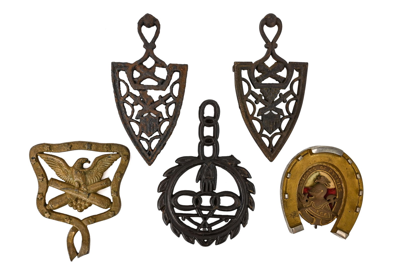 Five Cast Iron and Brass Trivets: Group of five decorative trivets, including a horseshoe-shaped Knights of Pythias fraternal trivet (5" L), a military-themed eagle and cannons trivet (7" L), an Independent Order of Odd Fellows (IOOF)