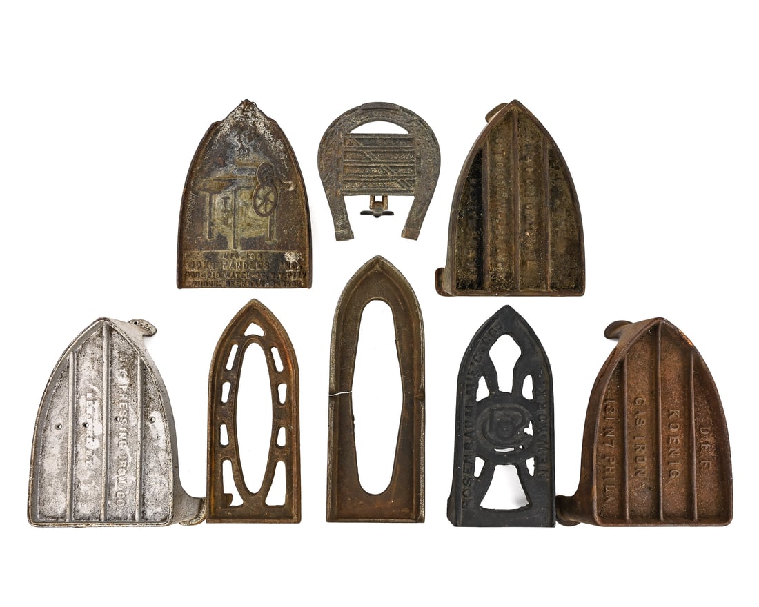 Heavy-Duty Cast Iron and Branded Trivets (8 pcs): Group of 8 heavy-duty trivets, mostly branded, including D.E.F. Koenig Gas Iron, NY Pressing Iron, Stockwell & Co., John Handles Inc., and Rosenbaum NY. Also includes a horseshoe trivet with stand and
