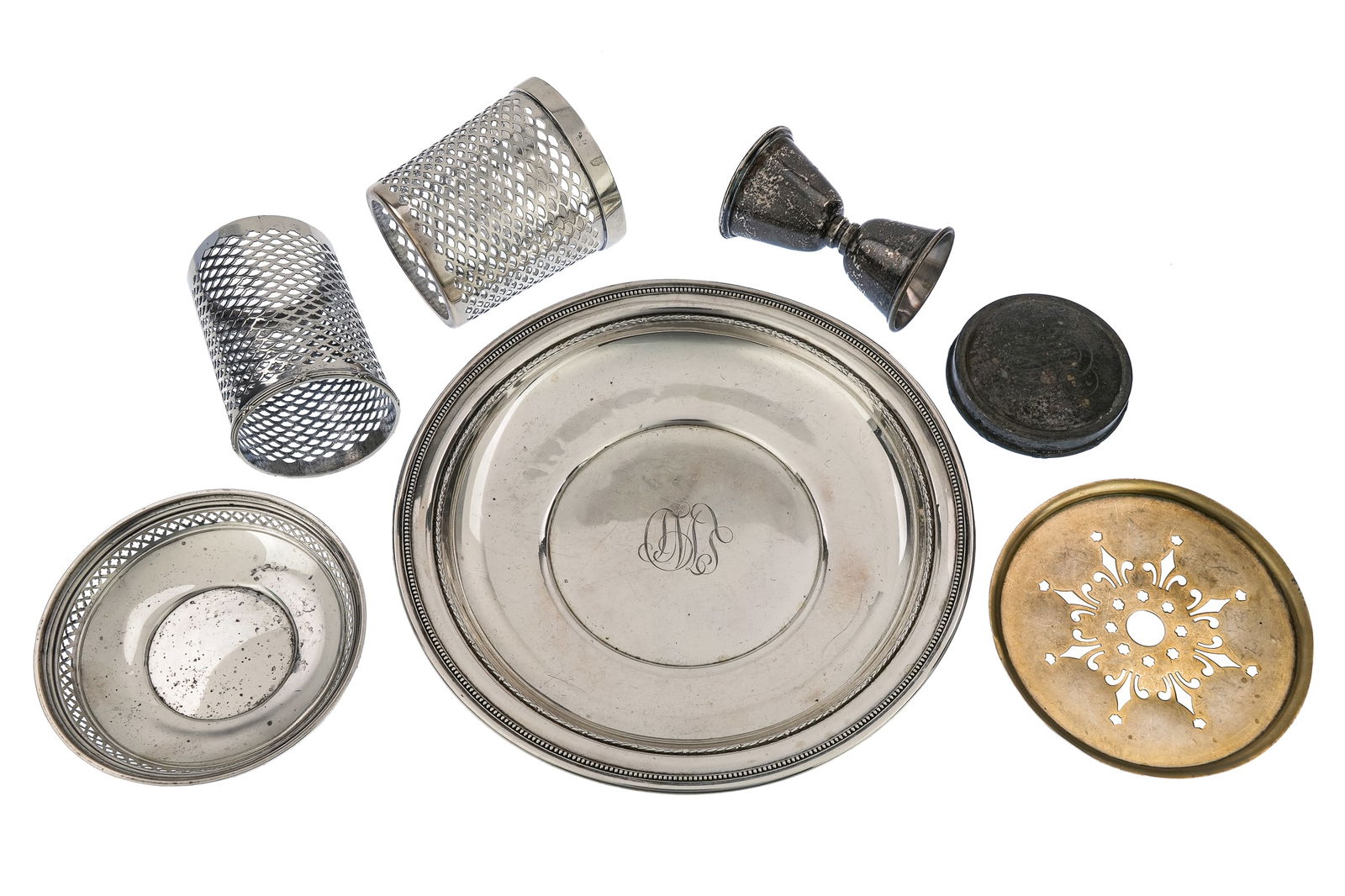 7 pcs. Sterling Silver Holloware: 7 pcs. of Sterling silver Holloware including serving plate, two reticulated cylinders, jigger bar measure, dresser jar lid, reticulated dish, and unmarked round butter dish liner (tests as sterling)