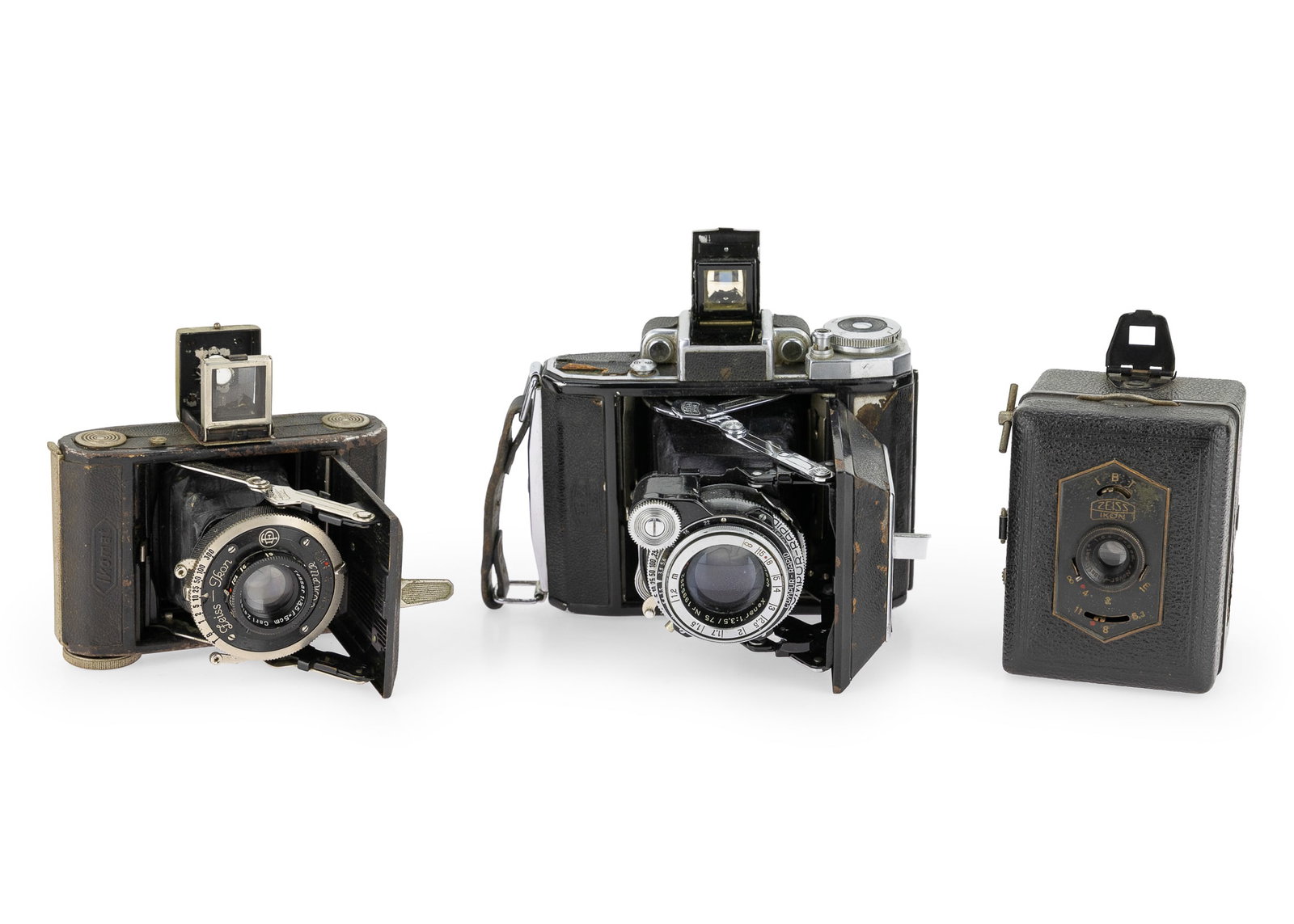 3 Zeiss Ikon Cameras: A group of 3 Zeiss Ikon cameras including a Compur Rapid Xenar 1:3,5 / 75 Nr. 1995392. A Ikomat Compur Jena Nr. 1253644 Tessar 1:3,5 f=5 cm. And a Baby box.
