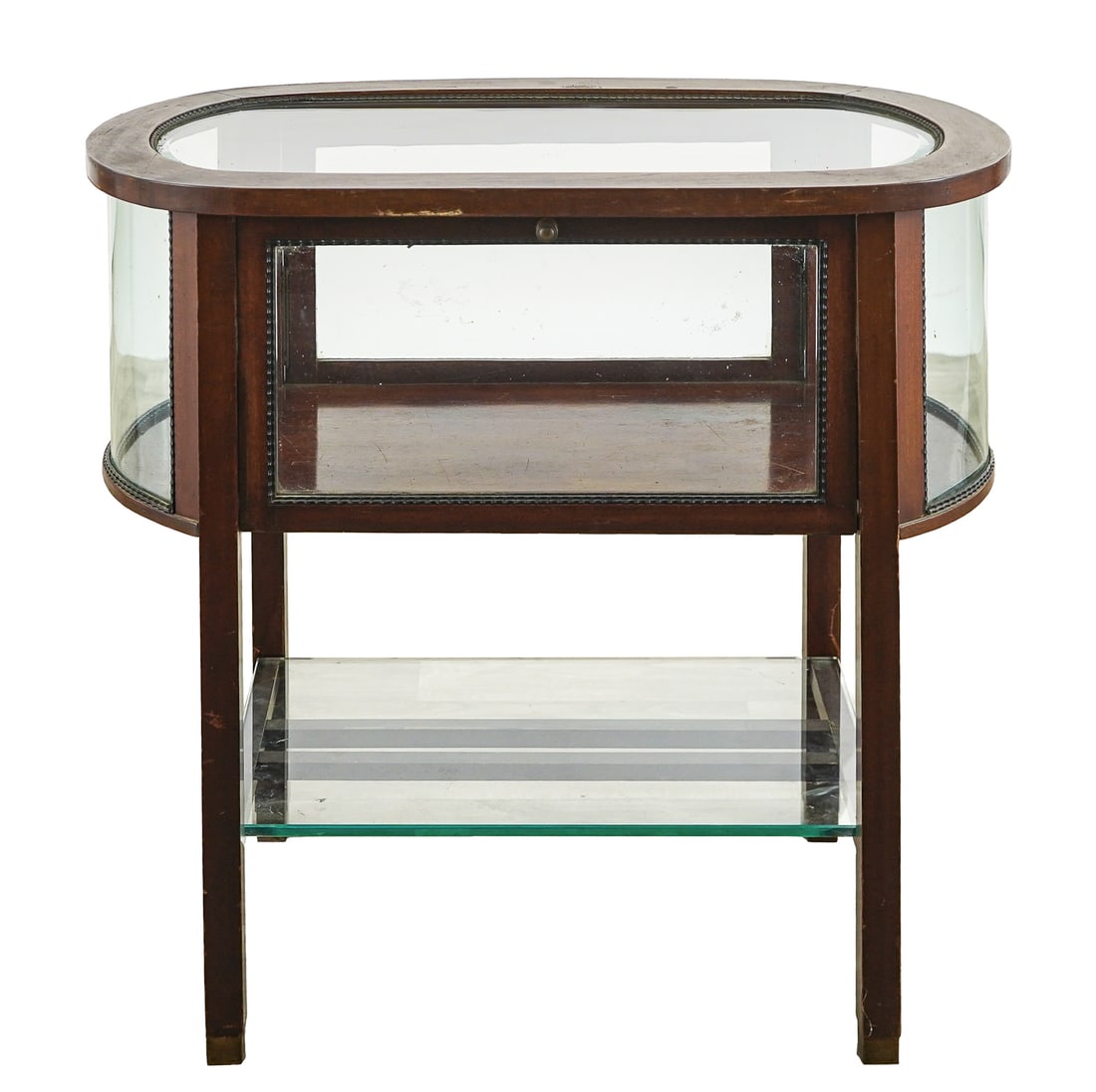 Mahogany Oval Curio Side Table: Mahogany oval curio cabinet. Curved glass ends, glass top, and glass sides. Gilt ribbon molding. Drop side door. Lower stretcher base with a plate glass shelf. 30" long, 17" wide, 29" h. Good