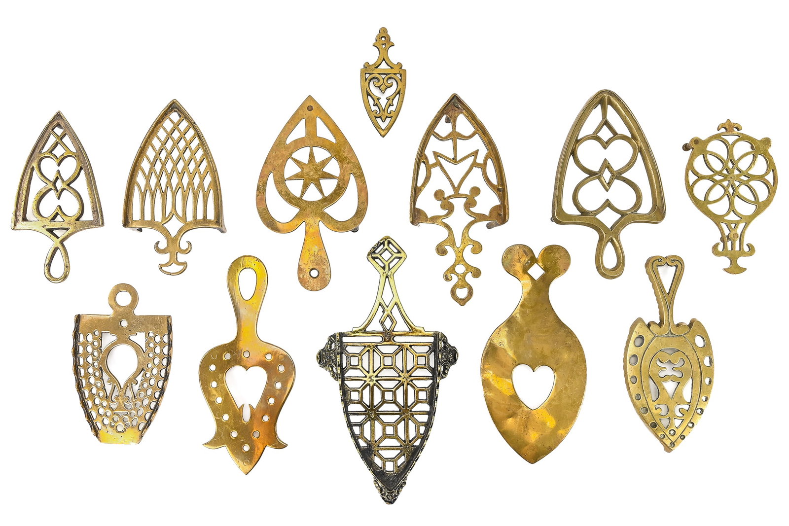 Group of 12 Brass Trivets: Twelve polished brass trivets with geometric, star, heart, perforated, and stippled designs. Largest measures approx. 11" L.