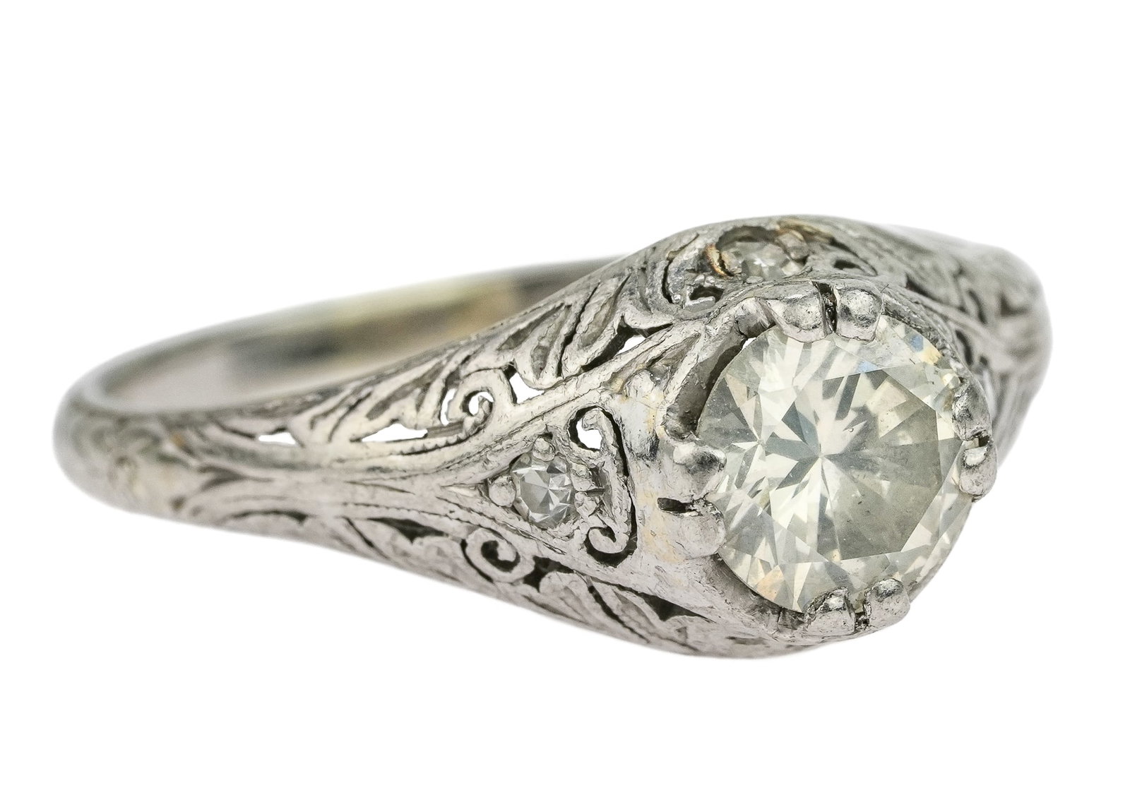 19k Art Deco 1 CT Diamond Ring: 19K white gold ring with high filigree setting having a European round cut approx. 1 CT diamond measuring 6.2 mm x 4 mm VS1, K. with 4 small diamonds in setting, 1 on each side. Marked 19k. Ring size 