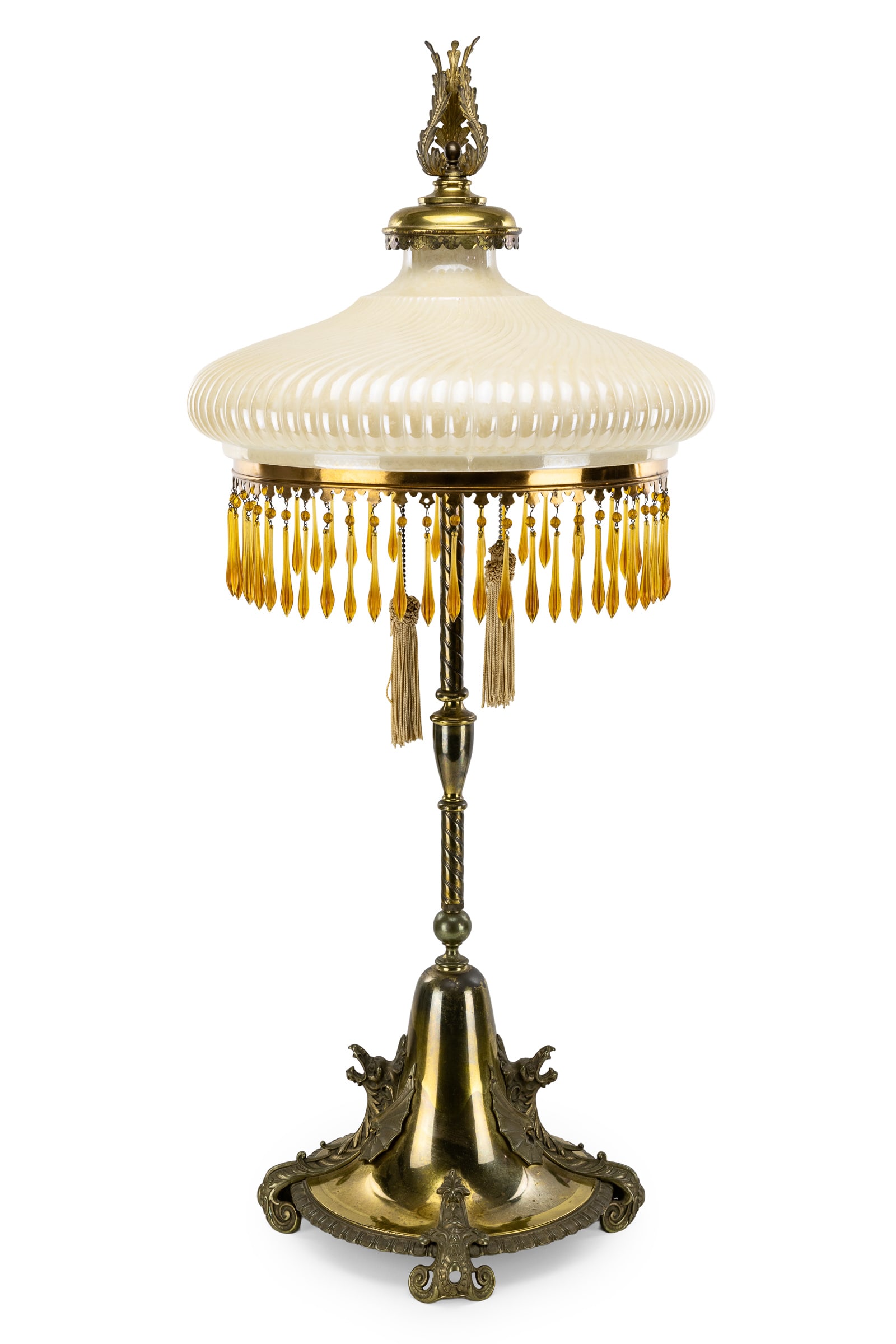 Art Nouveau Dragon Brass Table Lamp: Ca. 1900 Art Nouveau brass table lamp with ornate round base with appllied dragon heads & wings. Urn & rope twist brass column supporting a ribbed caramel toned glass luster shade having amber prisms.