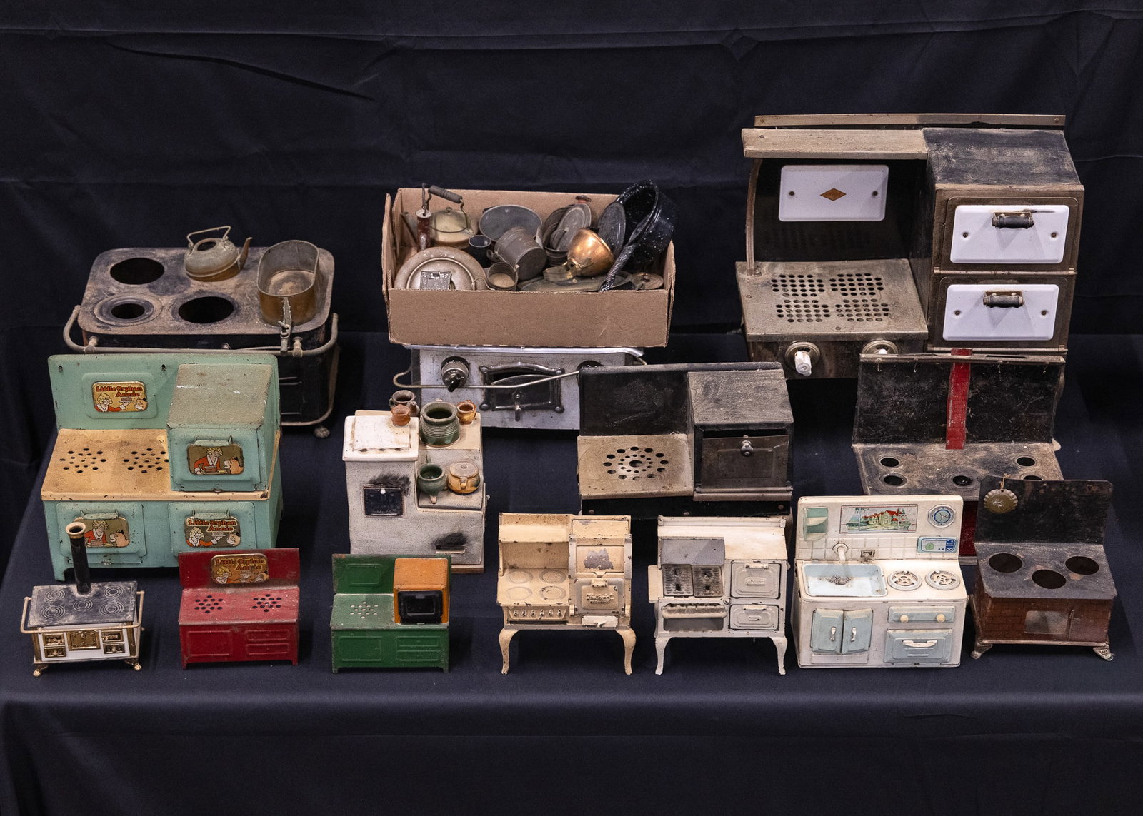 Tin and Pressed Steel Toy Stoves: 19th c- mid 20th c tinplate & pressed steel toy stoves (26 pcs) including Little Orphan Annie, sold with smaller cookware and accessories, stove widths 5" to 15"
