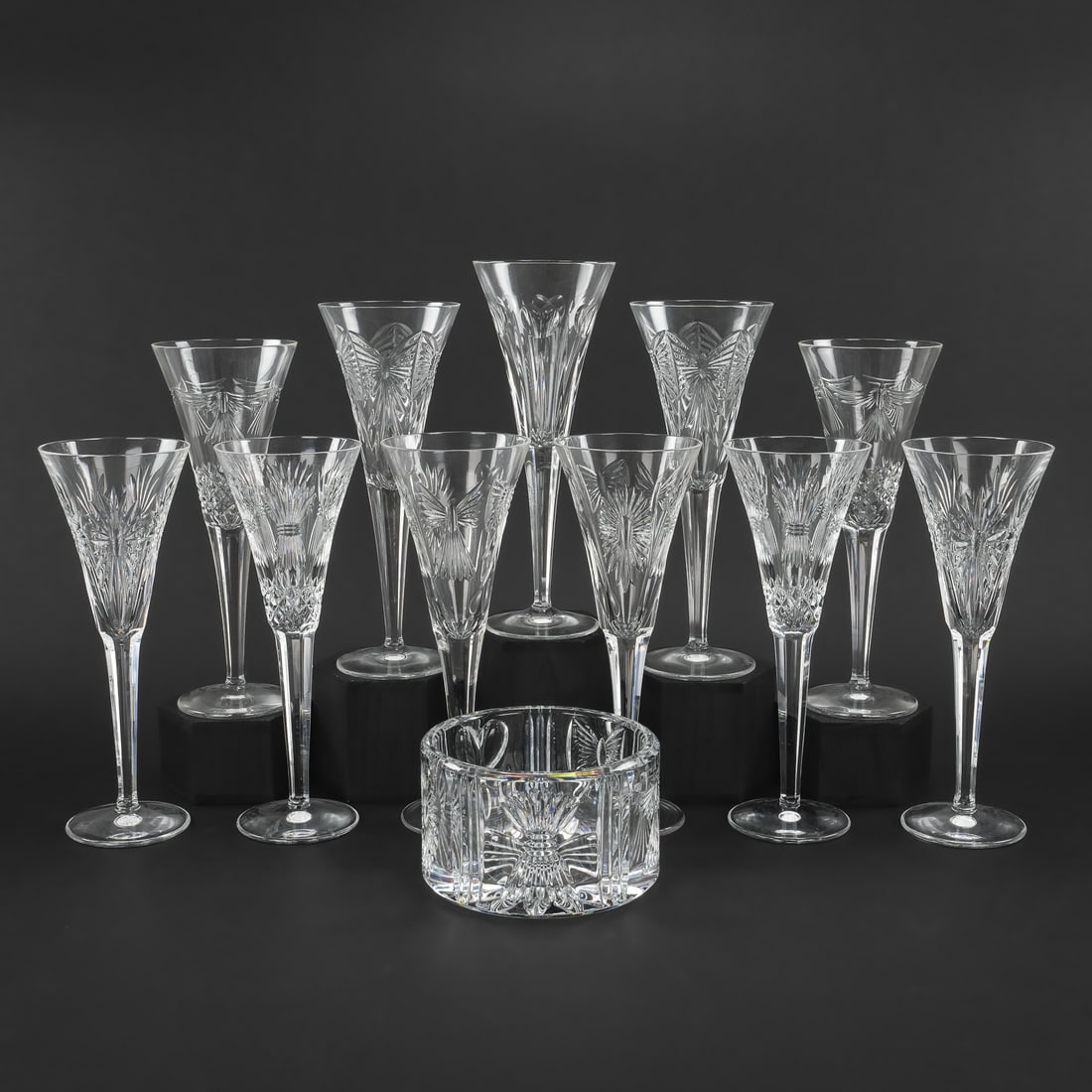 11 Waterford Champagnes and Bottle Coaster: Set of 11 Waterford "Millenium" Irish crystal champagne flutes, each bearing a different festive motif, accompanied by champagne bottle coaster. ht. 3.25"-9.25"