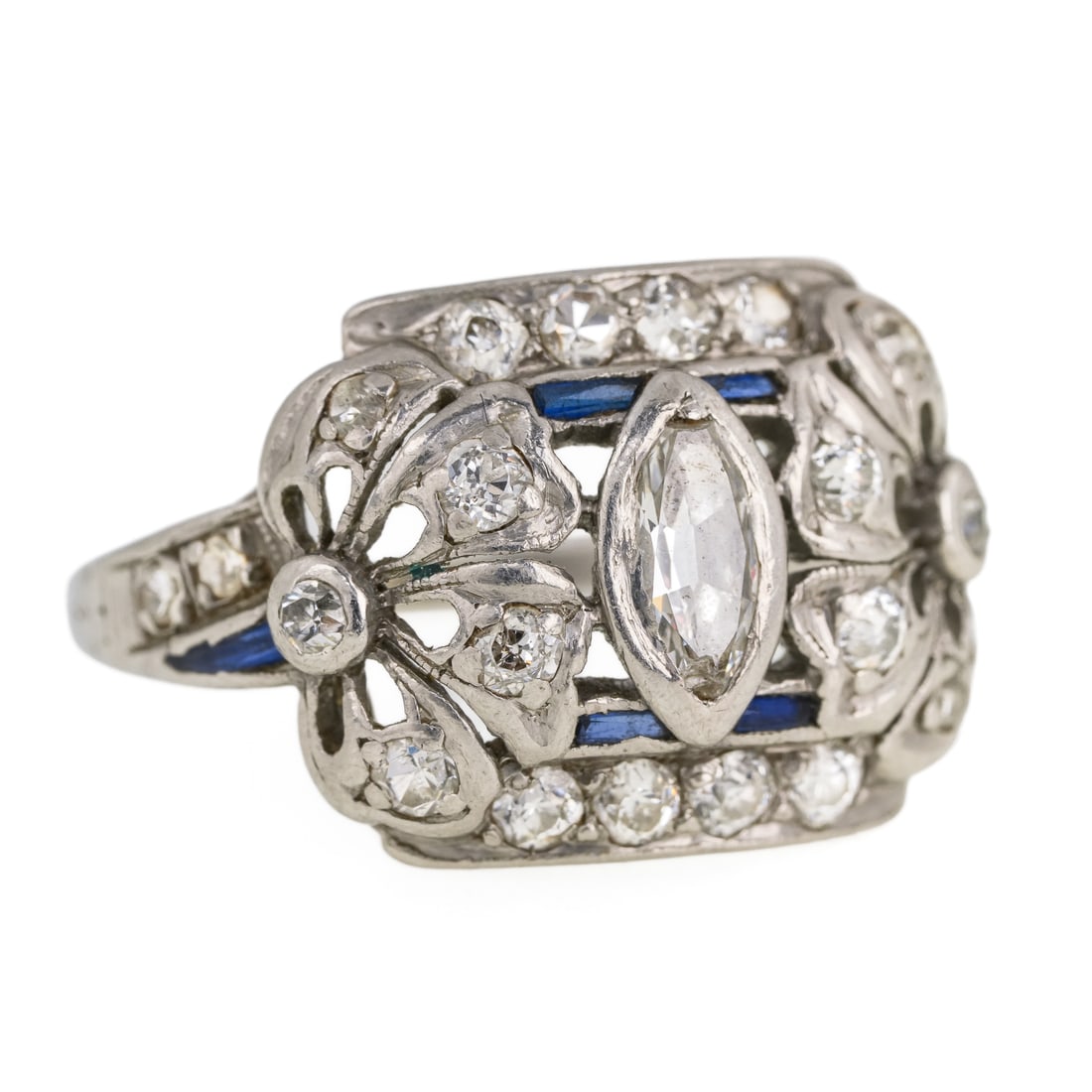Edwardian Platinum, Diamond, & Sapphire Ring: Edwardian platinum ring set with a center marquise cut 6.6 mm x 4 mm x 2.5 mm, .4 cts. Set with 22 .01 ct diamonds. Also with 6 baguette .01 ct sapphires in accents. Floral design. Ring size 6, 4.5