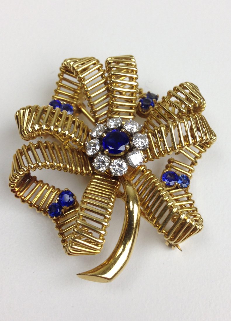 Signed Mellerio Paris 12772 18k y.g. clip brooch in: Signed Mellerio Paris 12772 18k y.g. clip brooch in floral form having 4 ribbon pedals, each with 2.1ct rd cut sapphires, center of flower with ½ct round cut sapphire and 8.1ct rd cut diamond surroun