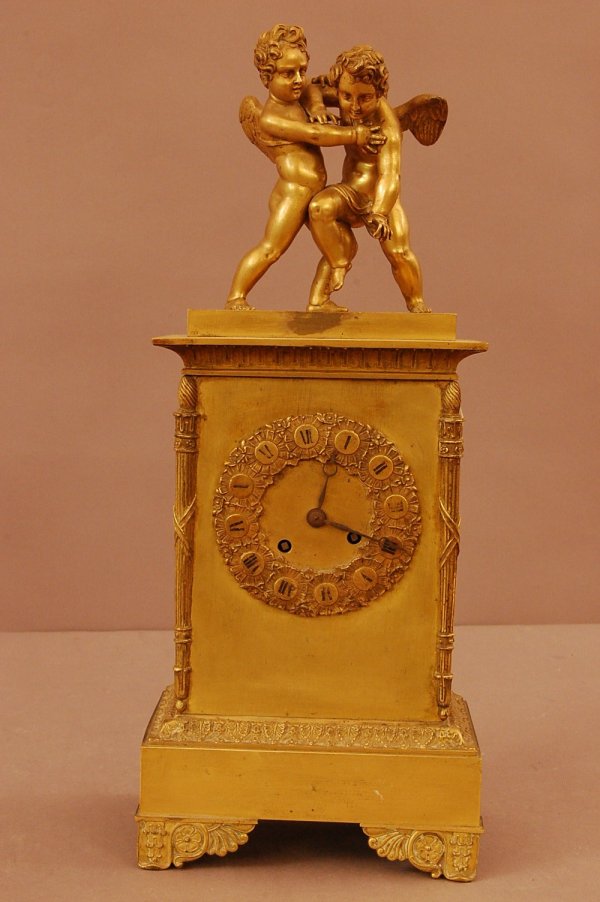 French Dore Bronze Figural Clock: French Dore Bronze Figural Clock, Empire Period clock with winged angels mounted on top, embossed dial, missing some parts, 18"T X 7"L X 5"d
