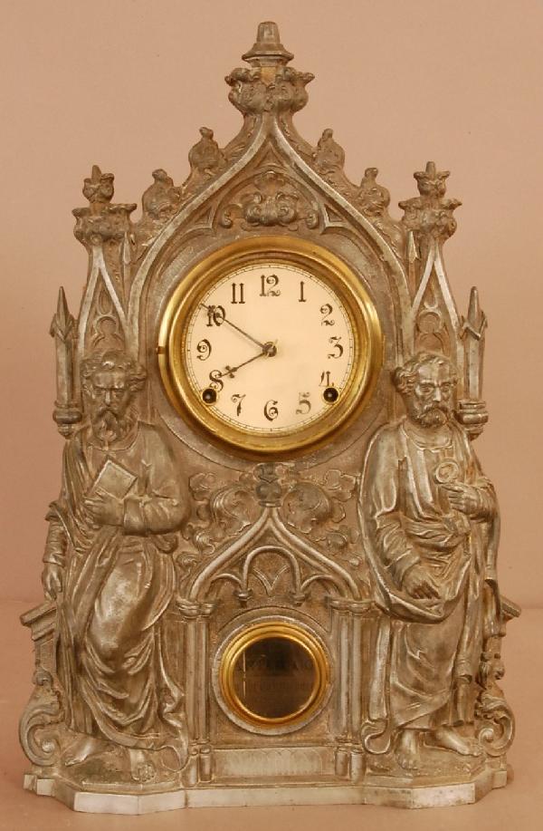 M.Muller #44 Shelf Clock: Gothic Style M.Mueller mantel clock, 2 standing men on front. Metal Front, wood case, signed on front. Works manufactured by Waterbury Clock Co. 20" t x 12" w x 3 1/2"d Ca. 1890