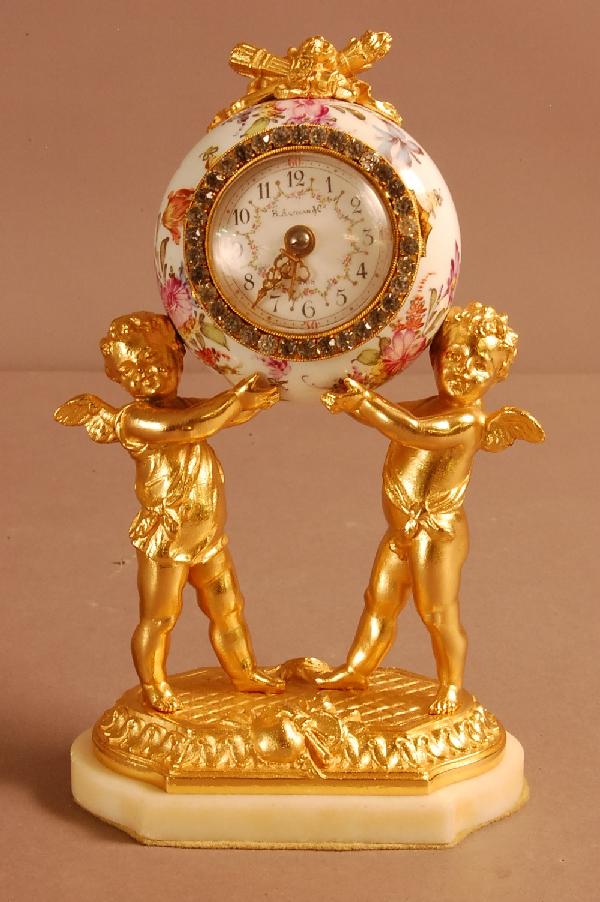 Dore Bronze French Louis XVI porcelain figural bou: Dore Bronze French Louis XVI porcelain figural boudoir clock with 2 cherubs holding up clock. Decorated Porcelain dial. Signed on marble base. A.R.A. etman & Co. Paris. 8" t x 4 1/2" w x 3" d Ca. 1800