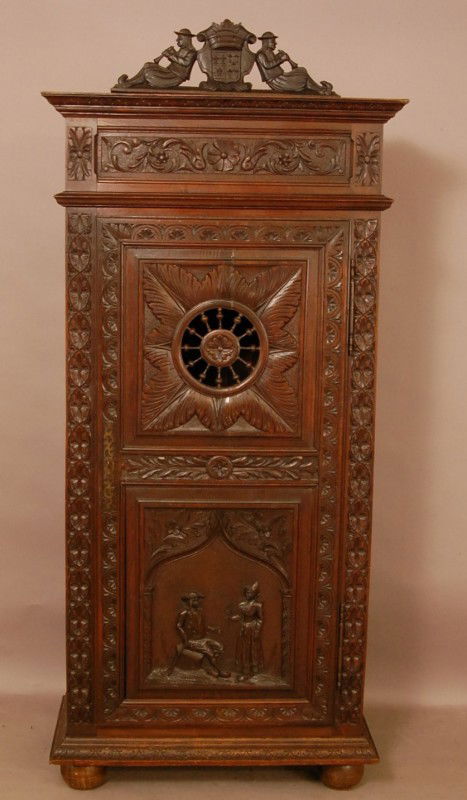 Brittany Style Oak armoire. Flute players leaning: Brittany Style Oak armoire. Flute players leaning on shield crest. Floral & leaf carving on sides, Wagon Wheel design on top panel of door, Man & Woman carved on lower panel. 78" t x 34" w x 17" d. Ca