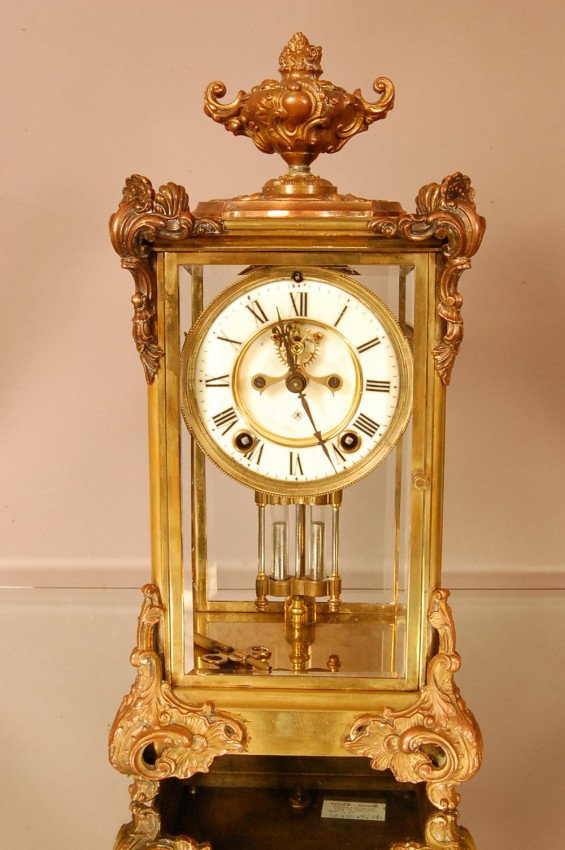 Ansonia Crystal Regulator with porcelain dial. Op: Ansonia Crystal Regulator with porcelain dial. Open escapement, time & strike. Beveled glass on all sides of Fancy brass decorative case. Clock works signed Ansonia, New York. 15" t x 6 1/2" d x 7 1/2