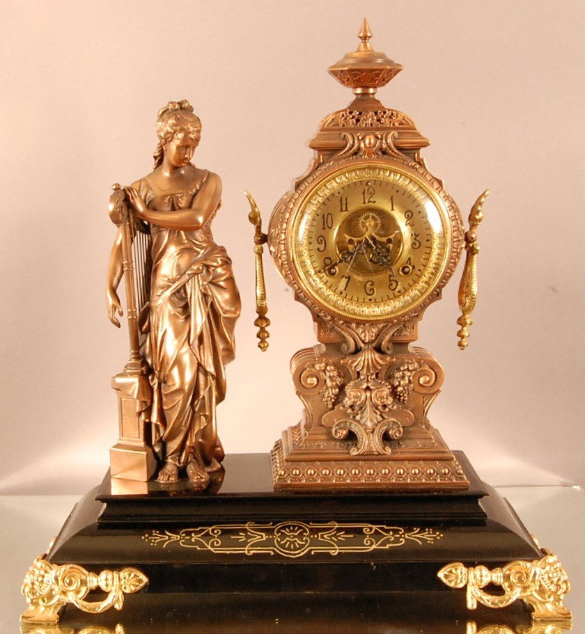 Ansonia Statue Clock with Spelter figure of woman : Ansonia Statue Clock with Spelter figure of woman standing on ebonized base. Time & Strike. Brass & Gilted dial with open escapement. 22" t x 20" w x 9" d Ca. 1890