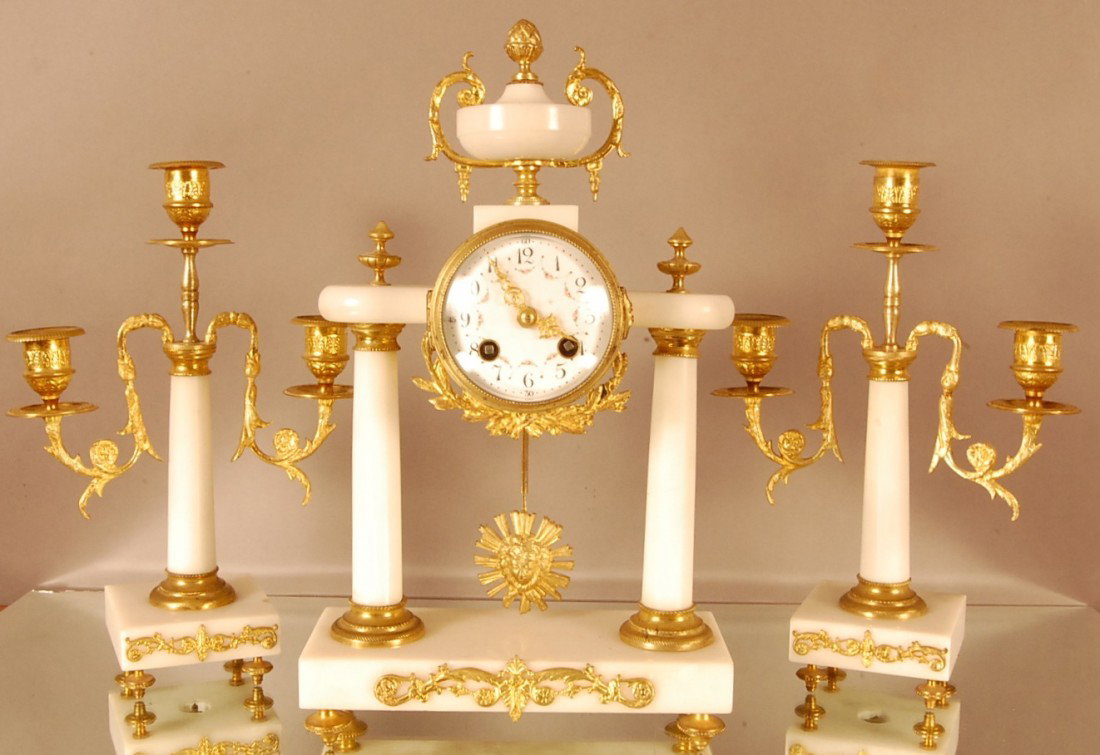 French Louis XVI style Dore Bronze 3 piece Clock S: Marble urn with bronze supports on top of clock. Double pillar supports on marble base. Decorated porcelain dial, time & strike works signed A.D.Mougin, with 2 matching candelabras. Clock 14" t x 9" w