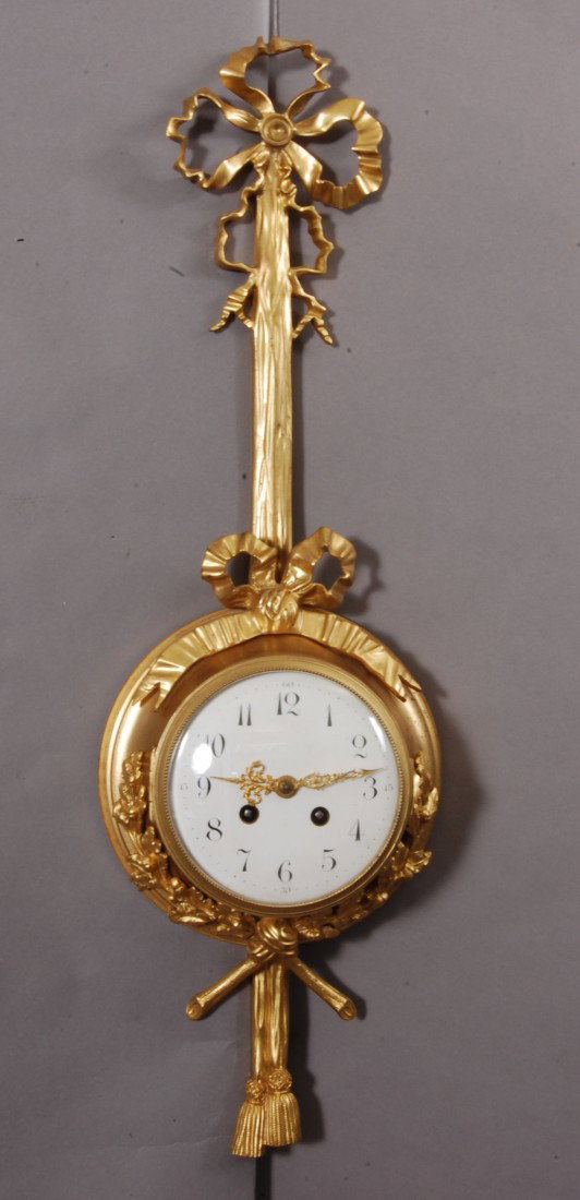French Louis XVI Dore Bronze Cartel Clock: Bronze Ribbon & Twig Decorations on top. Bronze leaf & acorn decorated on base. Porcelain Dial Time & Strike. Thirteen Jewel, Double adjustment movement. French Ca. 1890