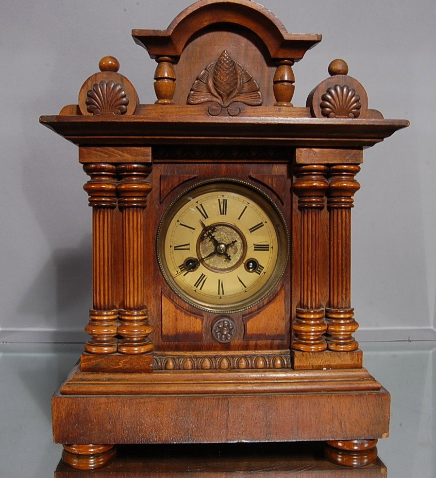 German Shelf Clock: Walnut case. Time & strike, carved crest, 4 fluted columns. 15" t x 11" w. Ca. 1890