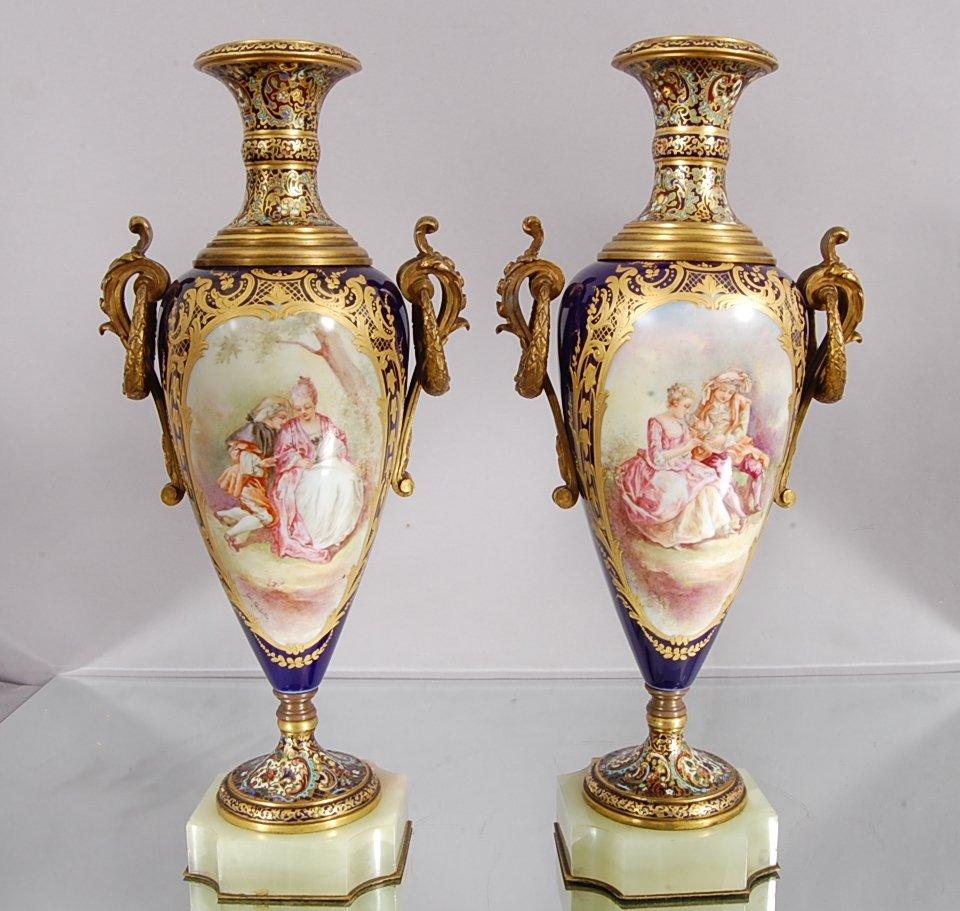 Pair of French Serves style Louis XV Urns: With cloisonne mounts on top & bottom. Hand Painted Romantic scenes. Front is mountain scene. Bronze handles. Artist signed Geo Rochelle Signed on Bottom. France. Ca. 1890