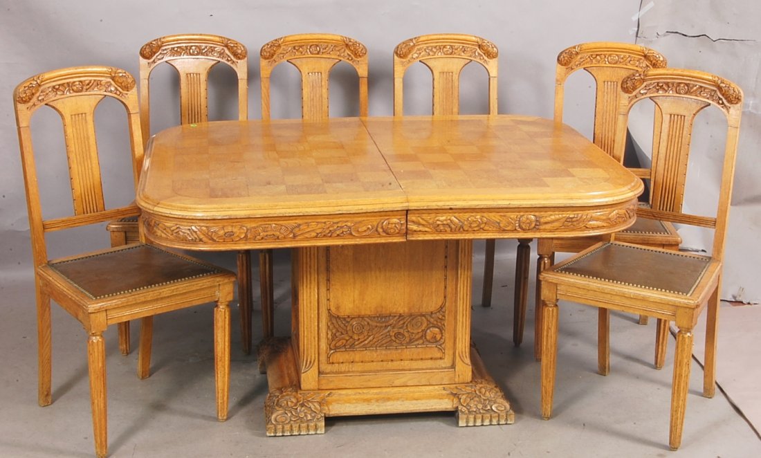 French Art Noveau style Oak Dining Room Set: With Marquetry extension table, floral carved skirt on square carved center pedestal with 6 matching chairs. Table 28" t x 53" l x 43" w; Chairs 38" t x 17" d x 18" w. Ca. 1910