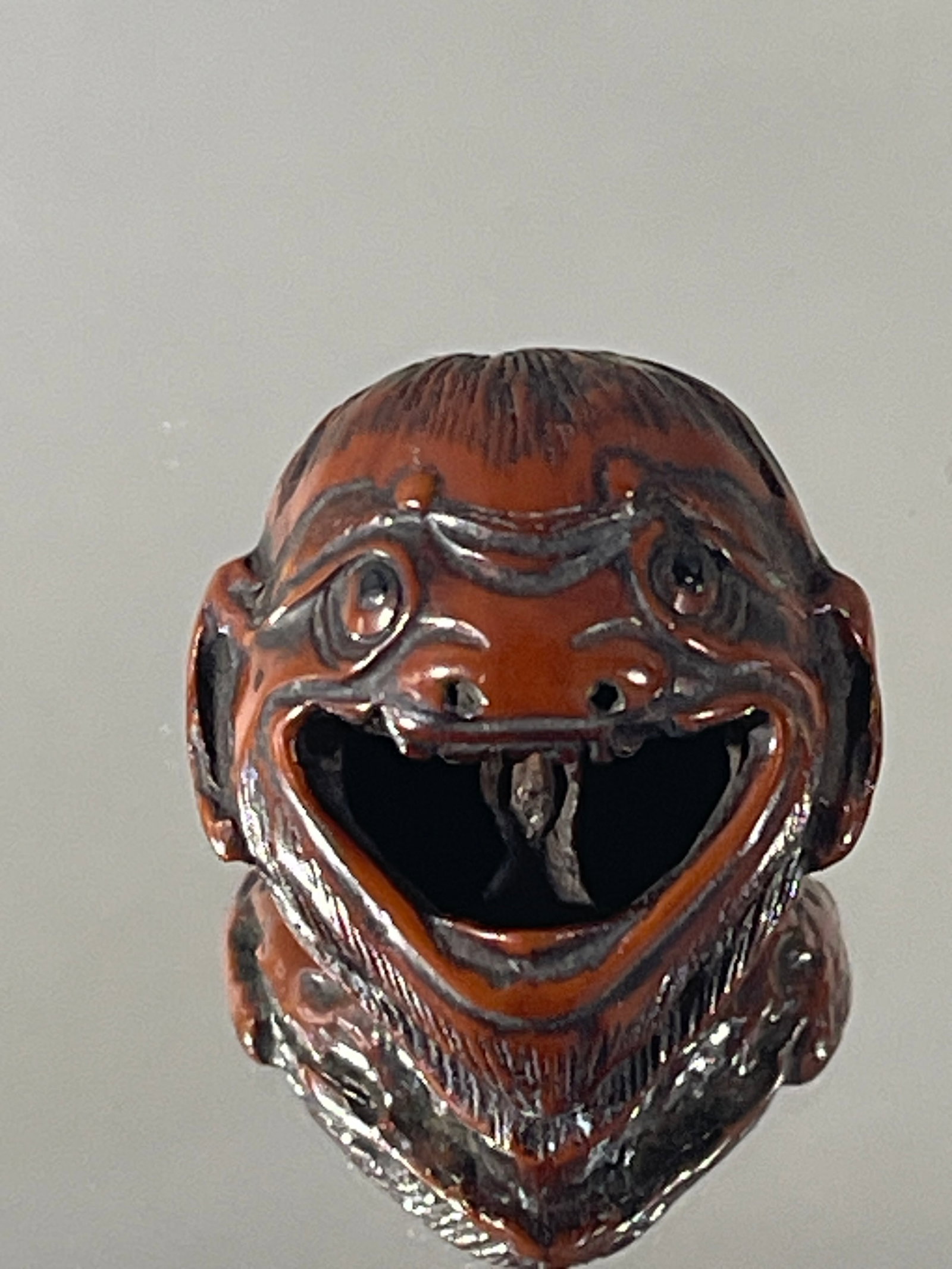 Minryosai: A Very Rare Kurumi Mask Netsuke: Carved from the kurumi (walnut) and depicting what Raymond Bushell describes as an "idiot head". The fitting description is owed to the grotesque nature of the carving- the mouth is opened wide reveal