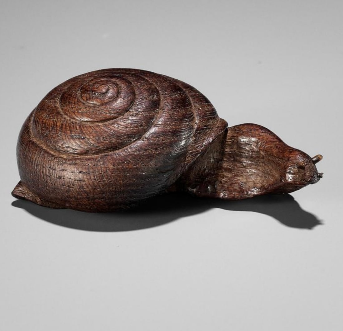 Yuzan: An Unusual Wood Netsuke of a Snail Emerging fro its Shell: Well carved to depict a snail in a rather unusual position with its body extended outward from its shell and head turned to one side the eyes inlaid with horn, the spiraling shell neatly incised. The 