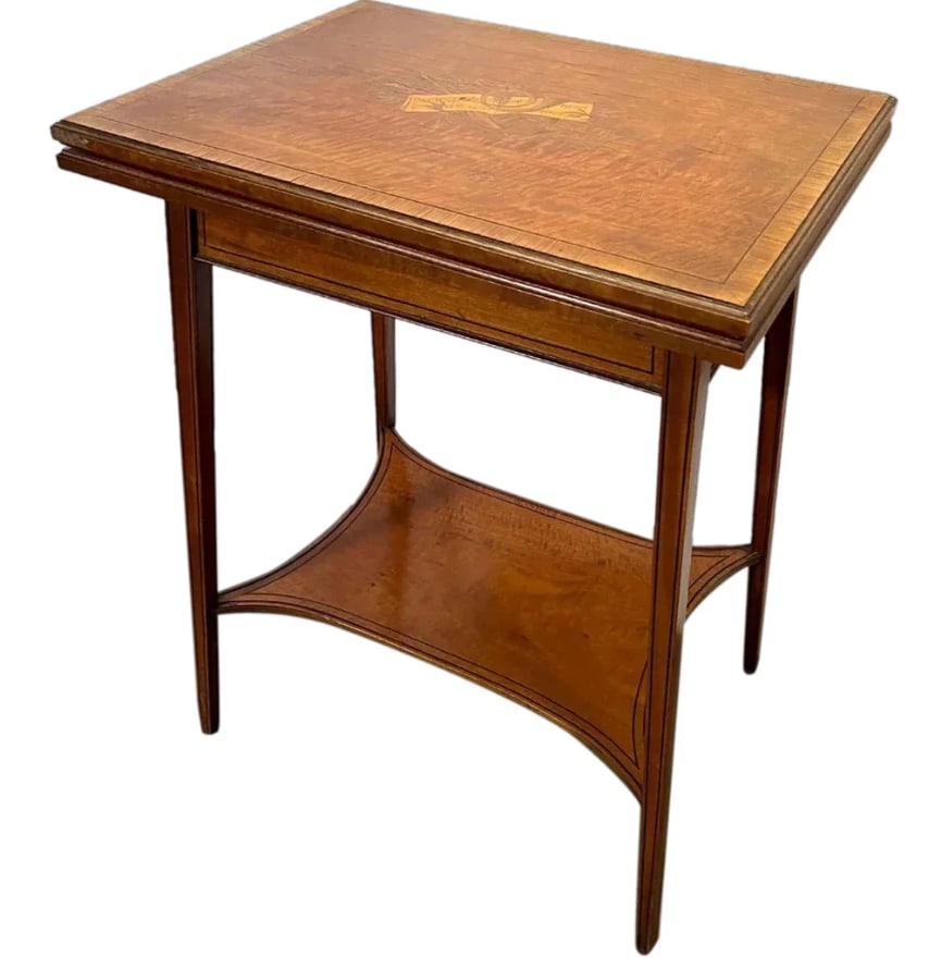 Signed English Edwardian Satinwood Marquetry Table: Signed English Edwardian Satinwood Marquetry Fold-Over Swivel Card Table. An antique games table with a rectangular top inlaid with sheets of music and instruments. It opens to a green baize felt moun