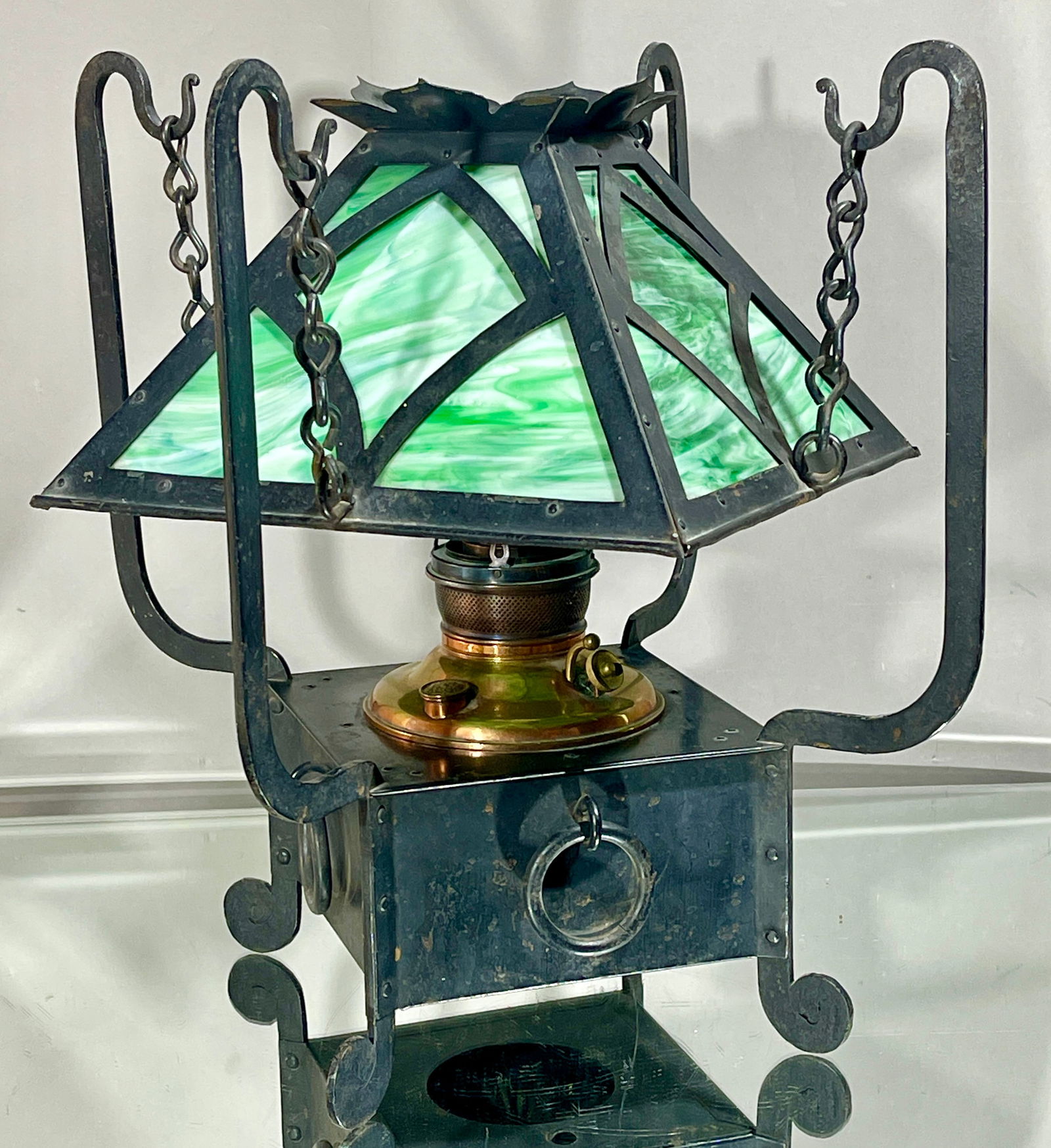 Arts & Crafts Wrought Iron Table Lamp: Iron shade with overlays on green slag glass panels. Has original kerosene burner. DIMENSIONS: 17"t x 17"w x 17"d ORIGIN: USA CIRCA: 1920.