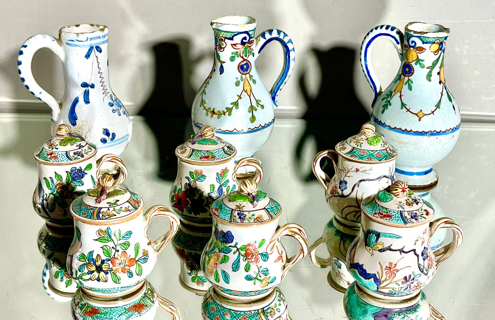 19th Century French Rouen Faience Chocolate Sets: Three chocolate pitchers, six covered cups, hand painted design featuring floral, foliate, and geometric. MARKS: cups are marked on bottom CONDITION: some losses DIMENSIONS: pitchers 5 3/4"t x 3"d x