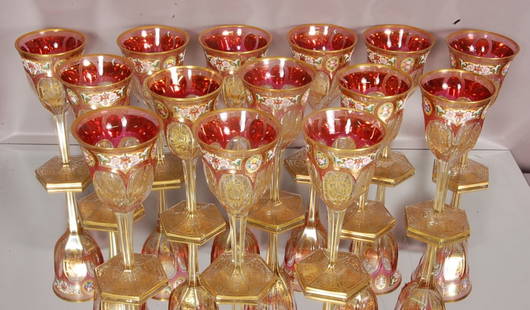 Decorated Wine Goblets: Cranberry cut to clear with raised enamel hand painted floral decoration & gilted trim. Set of 14. 8" t x 3 1/2" d. Hand blown ground base. Ca. 1920