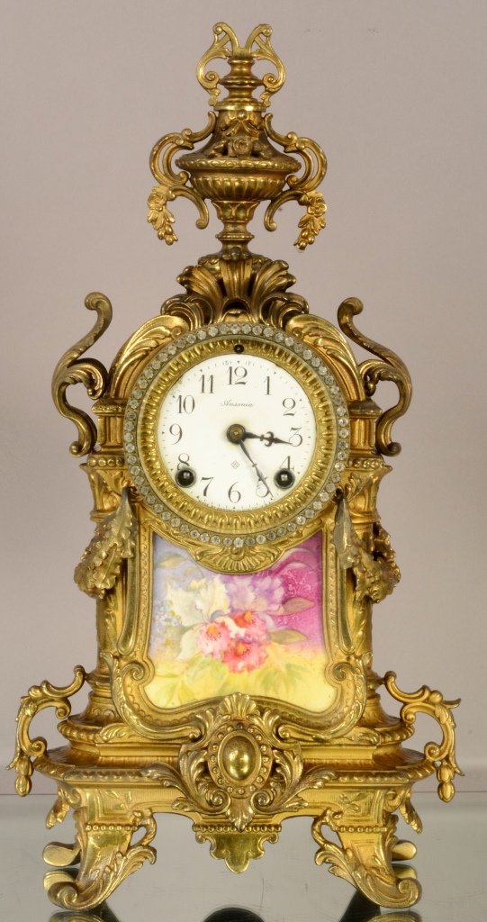 Ansonia Louis XV style mantel clock: With Serves style porcelain floral decorated panel. Bronze plated on case. Porcelain dial. Time & strike. 17" t x 10" w. Signed works & dial. Ca. 1880