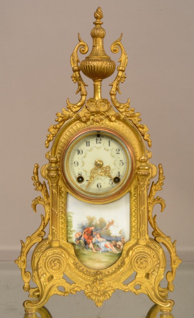 New Haven Louis XV style Bronzed & Porcelain mantel clo: With flamed urn shaped finial decoration sides, roman porcelain panel in base, time & strike with decorated porcelain dial. Original paper label on back. 16" t x 9" w. Ca. 1890