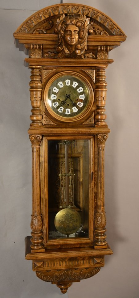 Gazo Walnut Clock with carved crest: Columns on sides, brass dial with porcelain numbers. Signed on door The Gazo Family Clock Factory. 58" t.