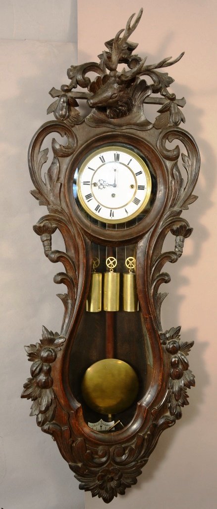 German Black Forest style Wall Clock: Carved deer head on top of clock. Heavily carved crest. 3 weight movement with porcelain dial. 48" t x 16" w. Ca. 1880