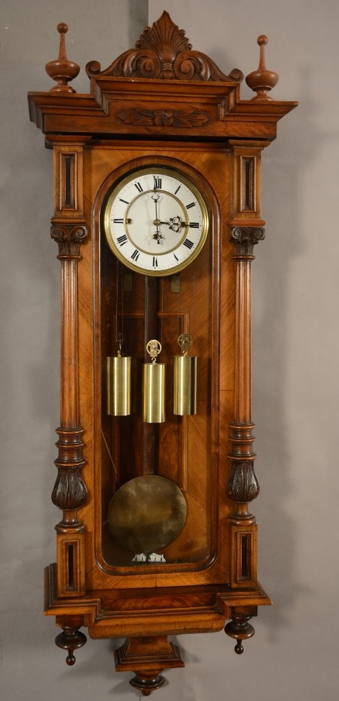 Vienna Regulator Wall Clock: Vienna Regulator wall clock. Three weight movement. Fancy walnut case with carved crest. Turned finials, fluted columns with shaped bottom. Porcelain dial. Time and 1/4 strike. ca. 1890. 48" tall
