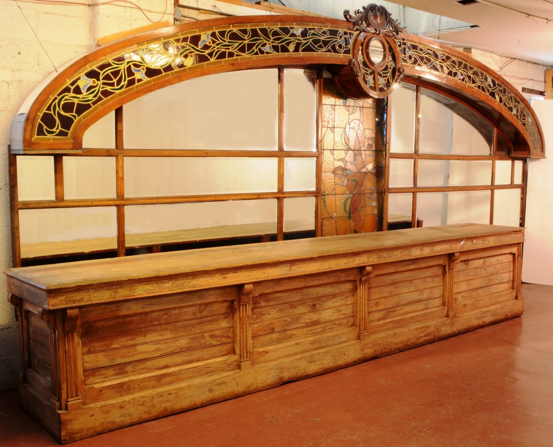 Unusual French Art Nouveau Style Oak Back Bar: Unusual French art nouveau style oak back bar with stain glass arched sides. Floral and leaf carved crest. 20 beveled mirrors in back. ca. 1910. Oak back bar 103" t x 22' L. Front bar 195" L.