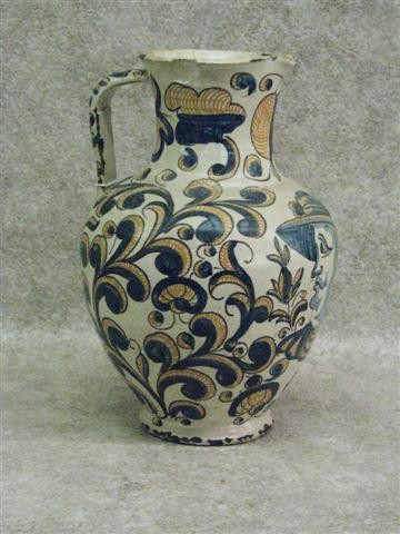 Talavera Faience Pitcher, Bold Fleur-de-lis Design: Talavera Faience Pitcher, Bold Fleur-de-lis Design in Blue and Burnt Orange, 11 1/2'' H x 7 1/2'' Dia. (at Widest Point), Some Chips to Glaze and Pitcher, Some Breaks and Repairs, $200-$350. Talavera