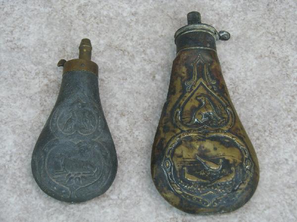 Powder or Shot Flasks, 2, Both with Images of Hunti: Powder or Shot Flasks, 2, Both with Images of Hunting Dogs and Game Birds in Relief, (A) Brass, 7 1/2'' L, (B) Possibly Zinc, 6'' L; from the Ware Family Collection, $100-$150.